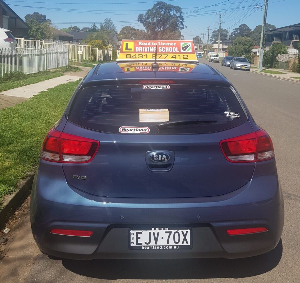 Road to Licence Driving School learner car with L-plate roof sign, parked on a St Marys street